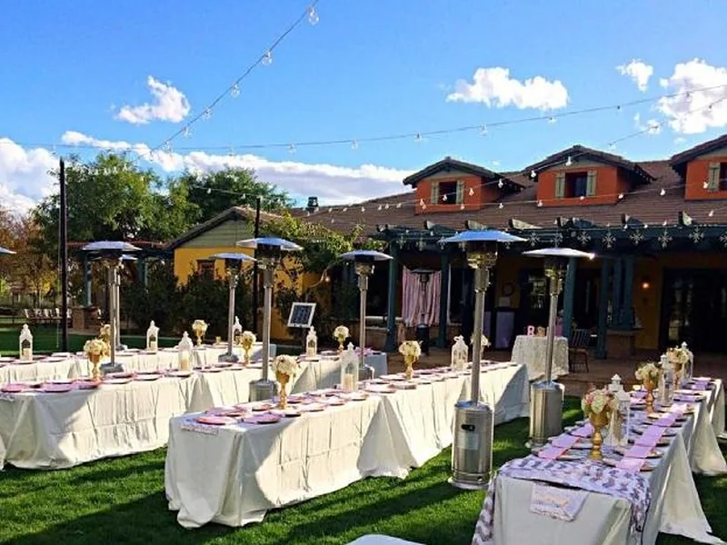 Propane patio heaters standing between long dressed tables at an outdoor reception under string lights