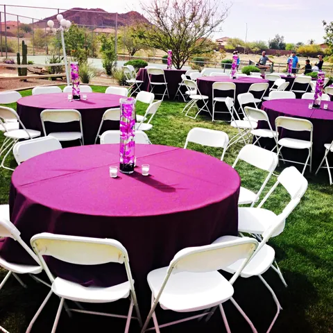 Round tables in purple linens with white folding chairs on a lawn