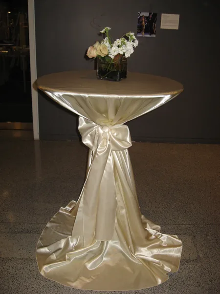 High-top cocktail table in an ivory satin floor-length linen gathered with a tie at the center