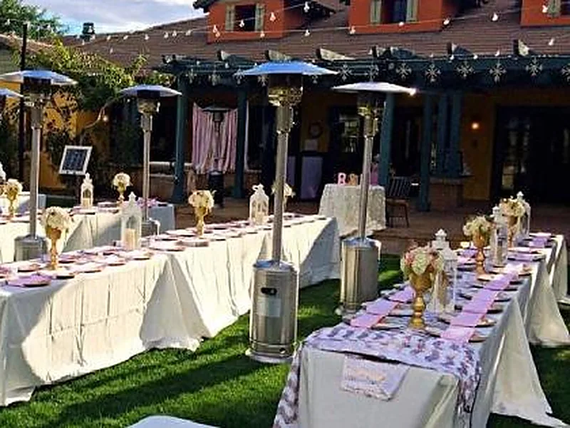Two propane patio heaters standing beside a long dressed banquet table at an outdoor reception