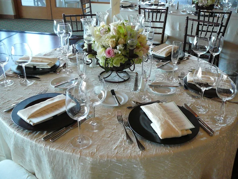 Round banquet table dressed in an ivory tablecloth with folded napkins and a floral centerpiece